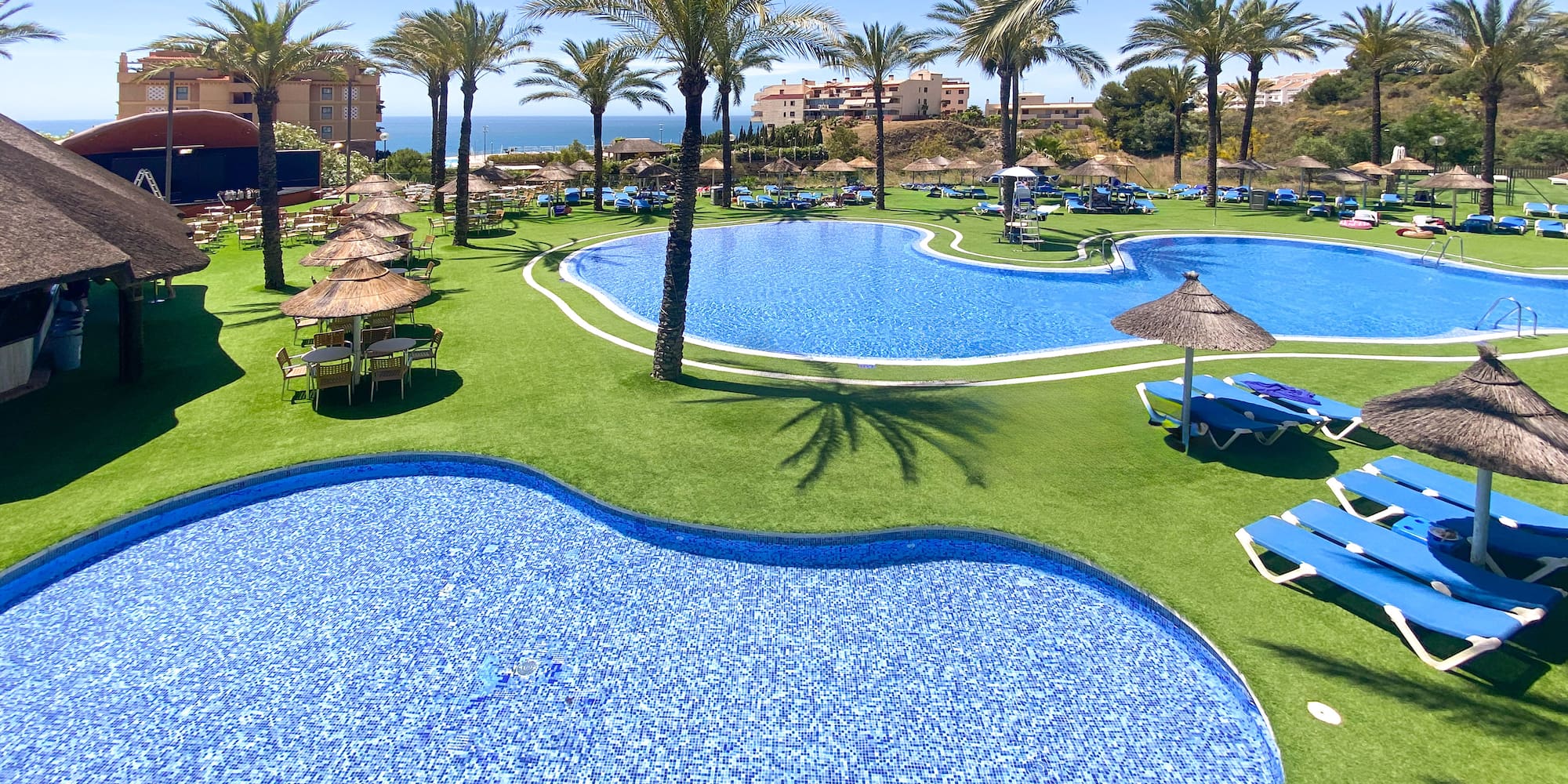 a pool with chairs and umbrellas on grass