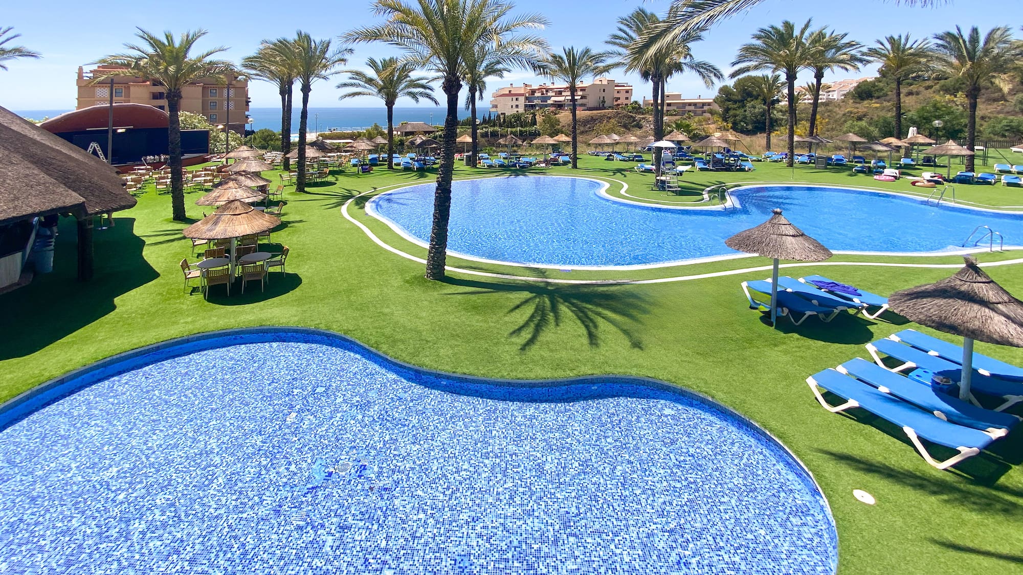 a pool with chairs and umbrellas on grass