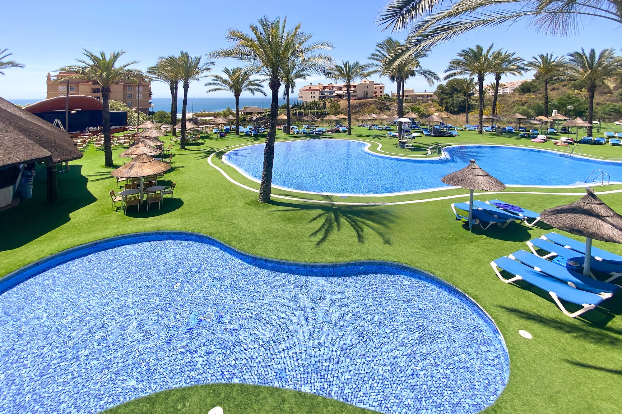 a pool with chairs and umbrellas on grass