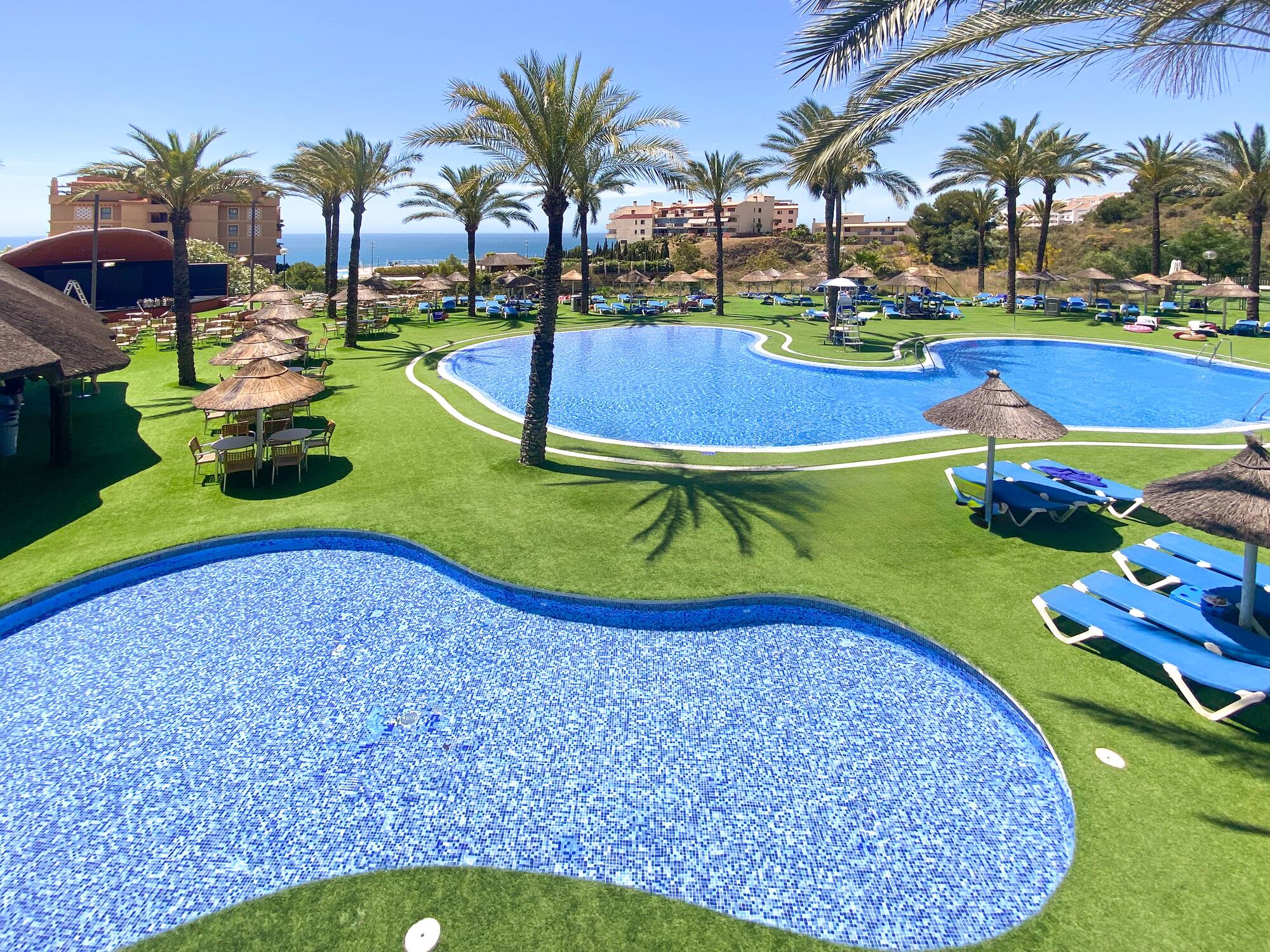 a pool with chairs and umbrellas on grass