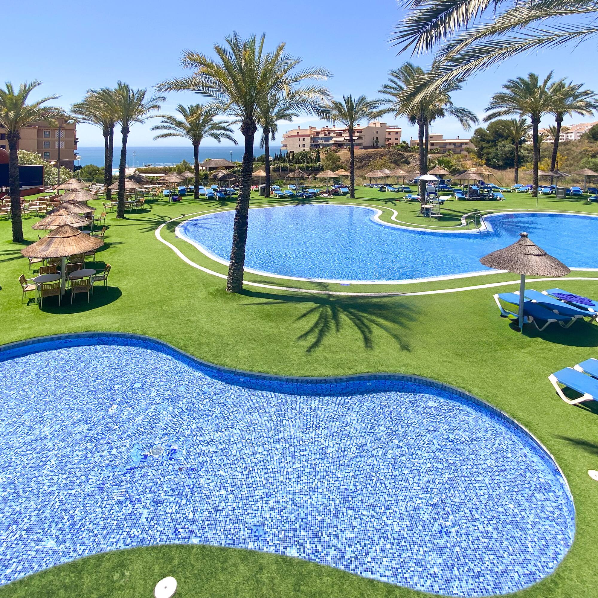 a pool with chairs and umbrellas on grass