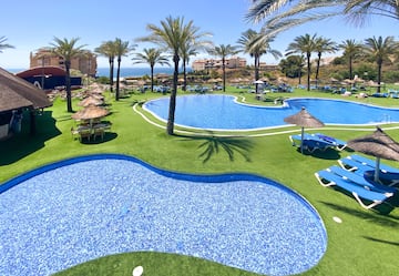 a pool with chairs and umbrellas on grass