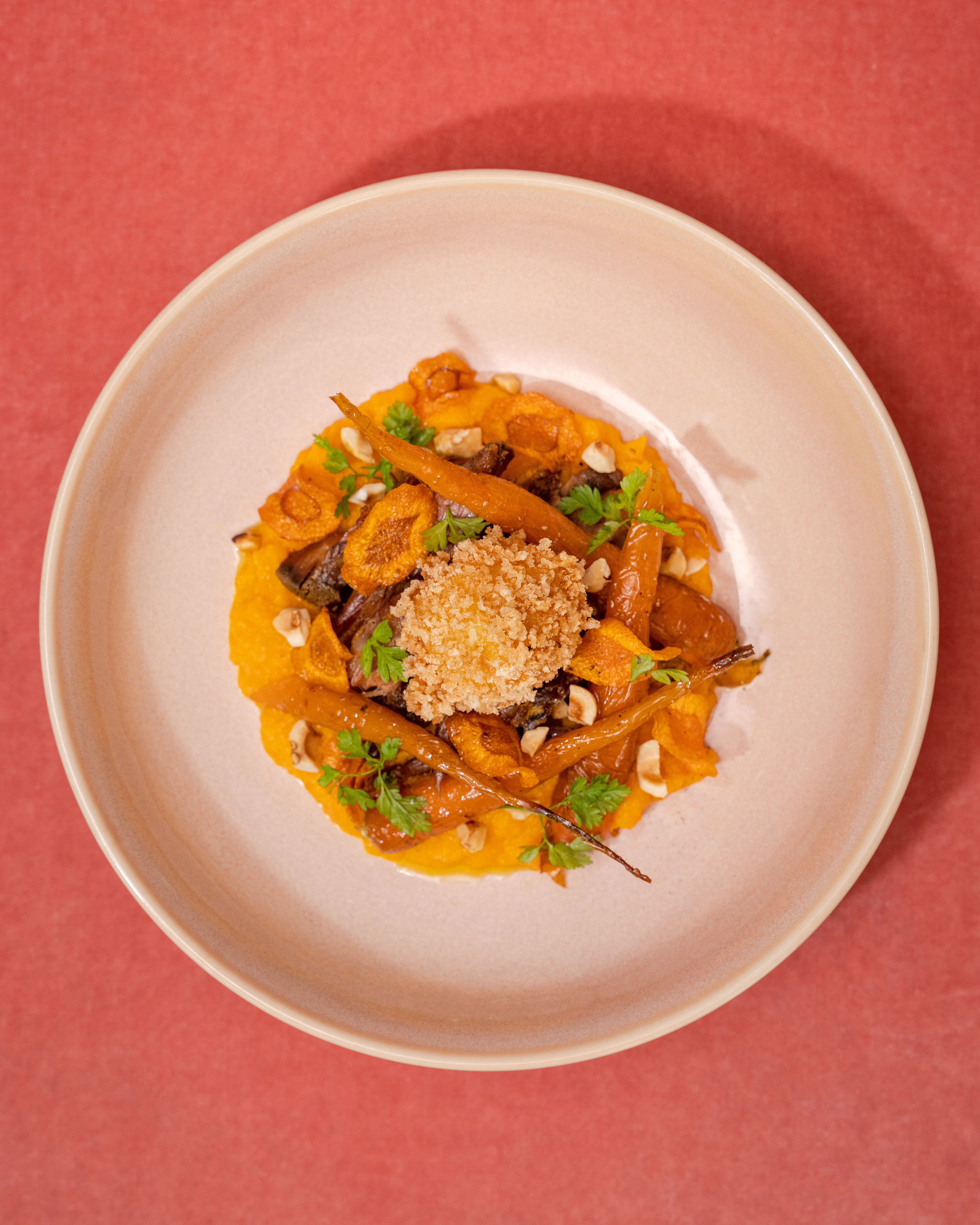 Roasted carrots on orange puree with crispy breadcrumbs, hazelnuts, and parsley.