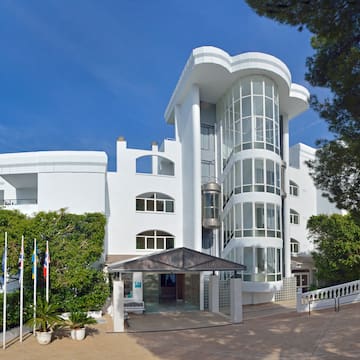 a white building with trees and flags