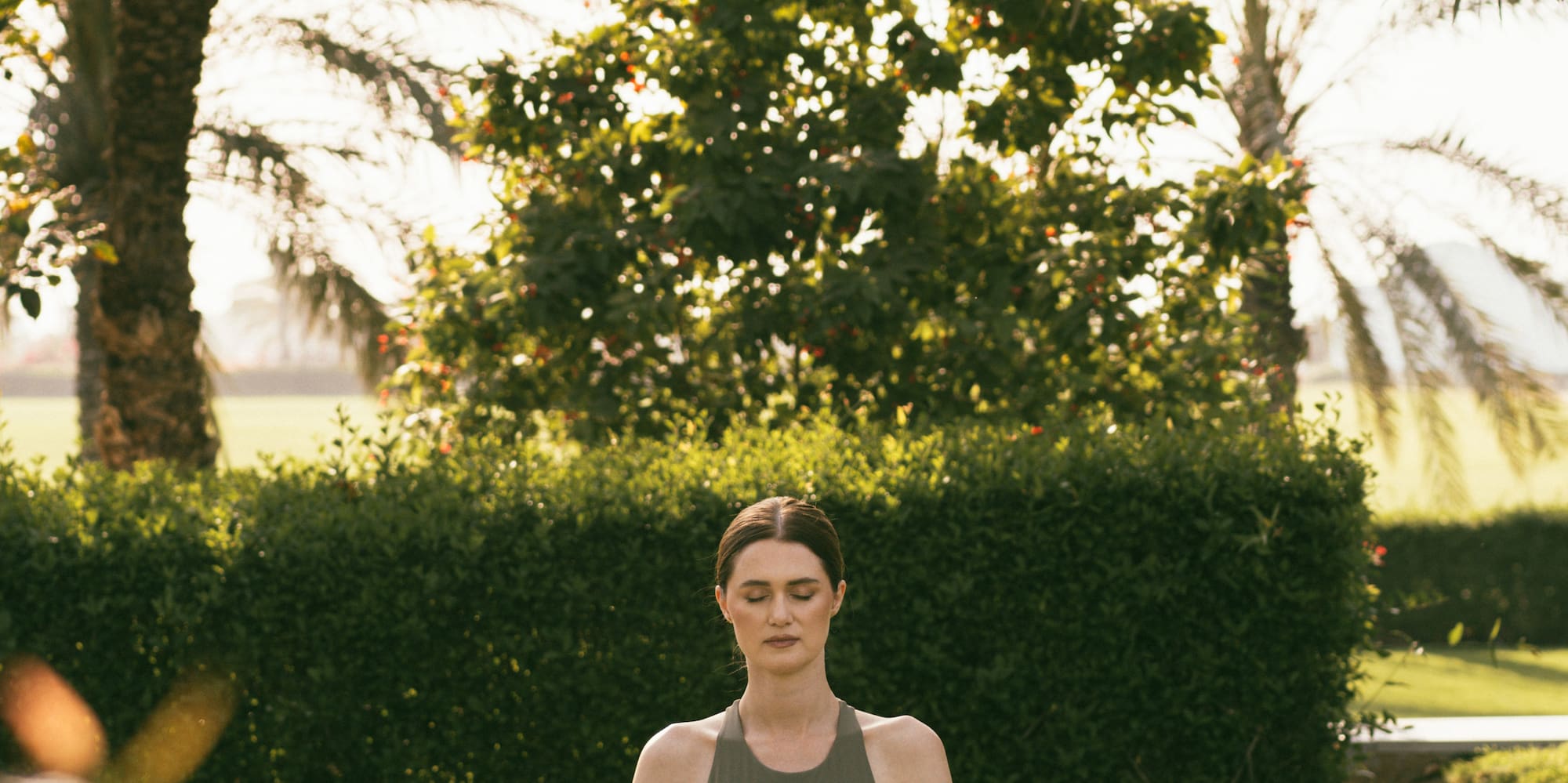 a woman sitting on a mat in a park
