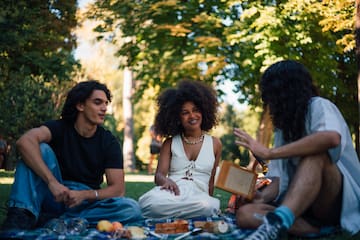 a group of people sitting on a blanket in a park