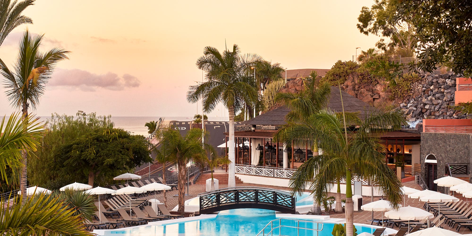 a swimming pool with umbrellas and chairs and a bridge