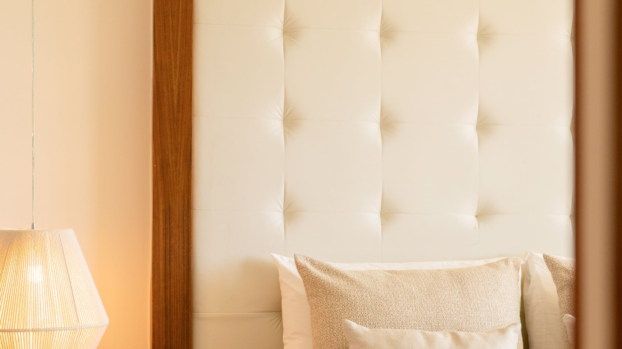 Cozy bedroom with cream tufted headboard, bedside lamp, and bed tray.