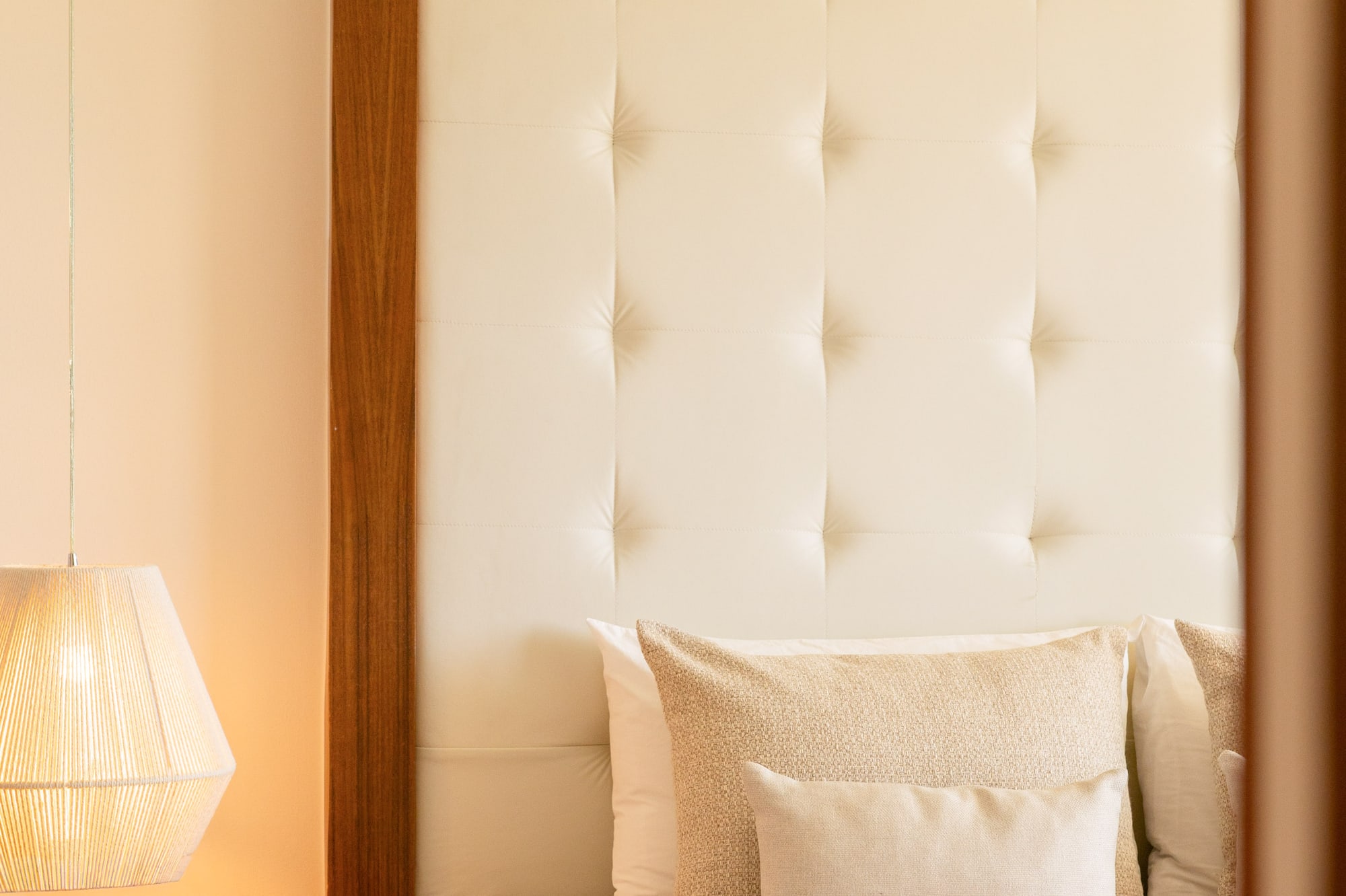 Cozy bedroom with cream tufted headboard, bedside lamp, and bed tray.