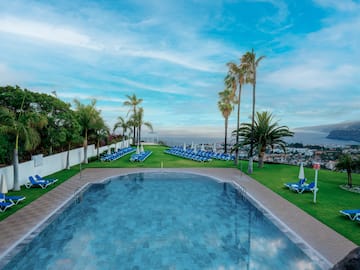 a pool with chairs and trees around it