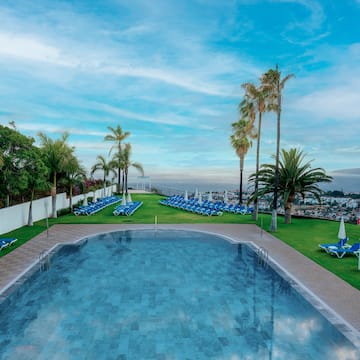 a pool with chairs and trees around it
