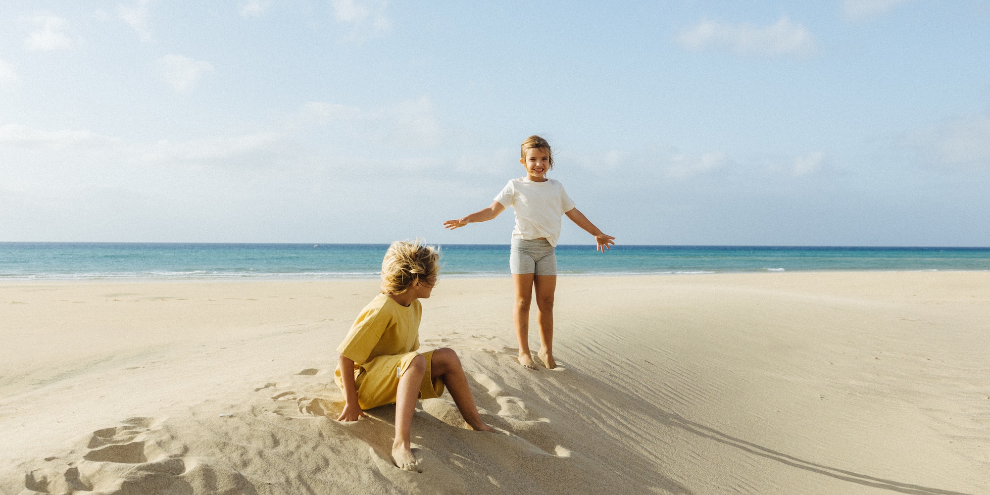 Happy kids playing on a sunny sandy beach with ocean.