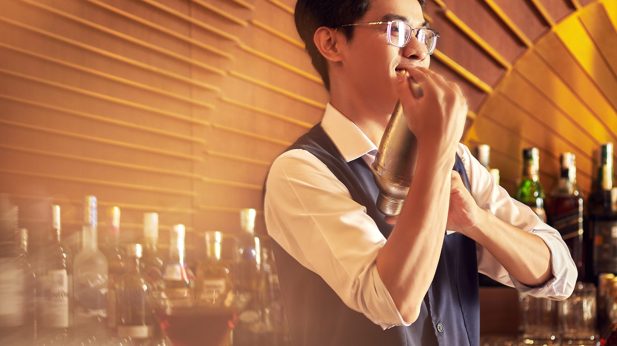 a man holding a shaker in front of a bar