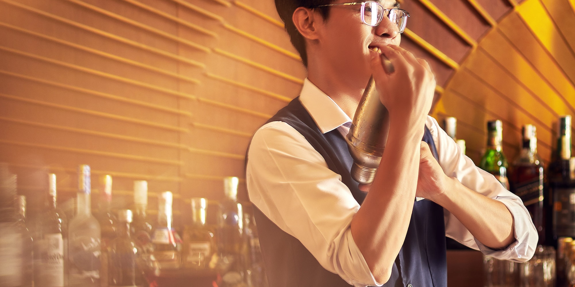 a man holding a shaker in front of a bar