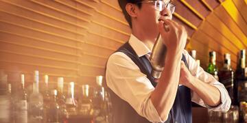 a man holding a shaker in front of a bar