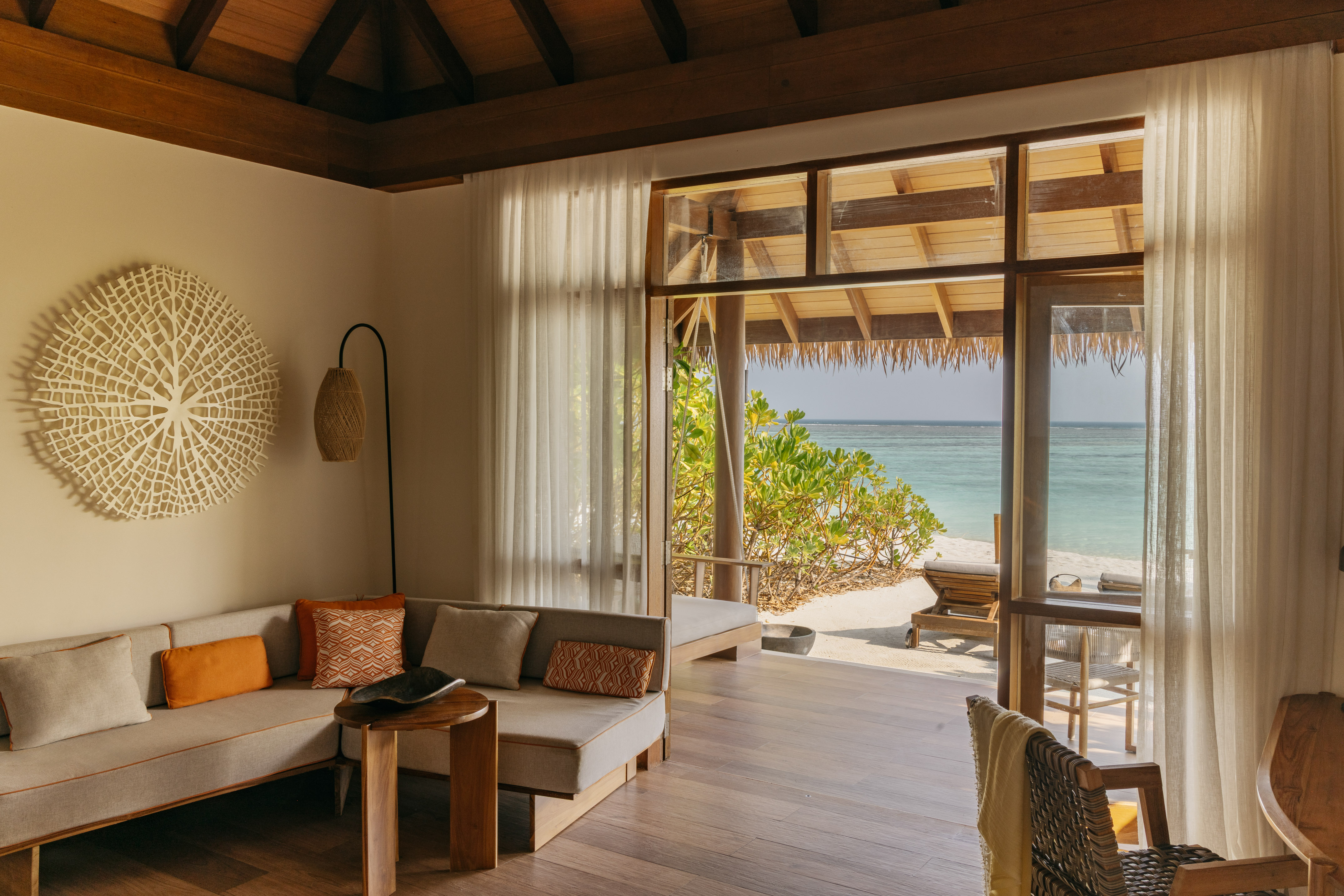 Beach villa living room with sofa, tropical accents, and ocean view.