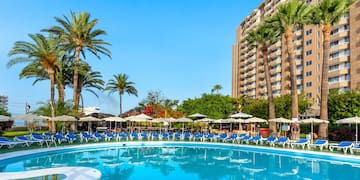 a pool with umbrellas and chairs in front of a building