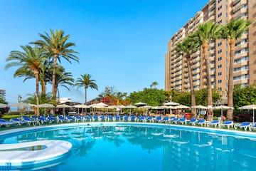 a pool with umbrellas and chairs in front of a building