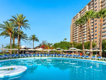 a pool with umbrellas and chairs in front of a building