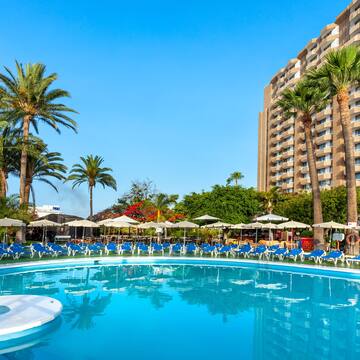 a pool with umbrellas and chairs in front of a building