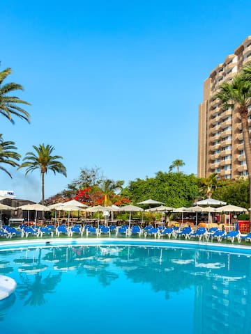 a pool with umbrellas and chairs in front of a building