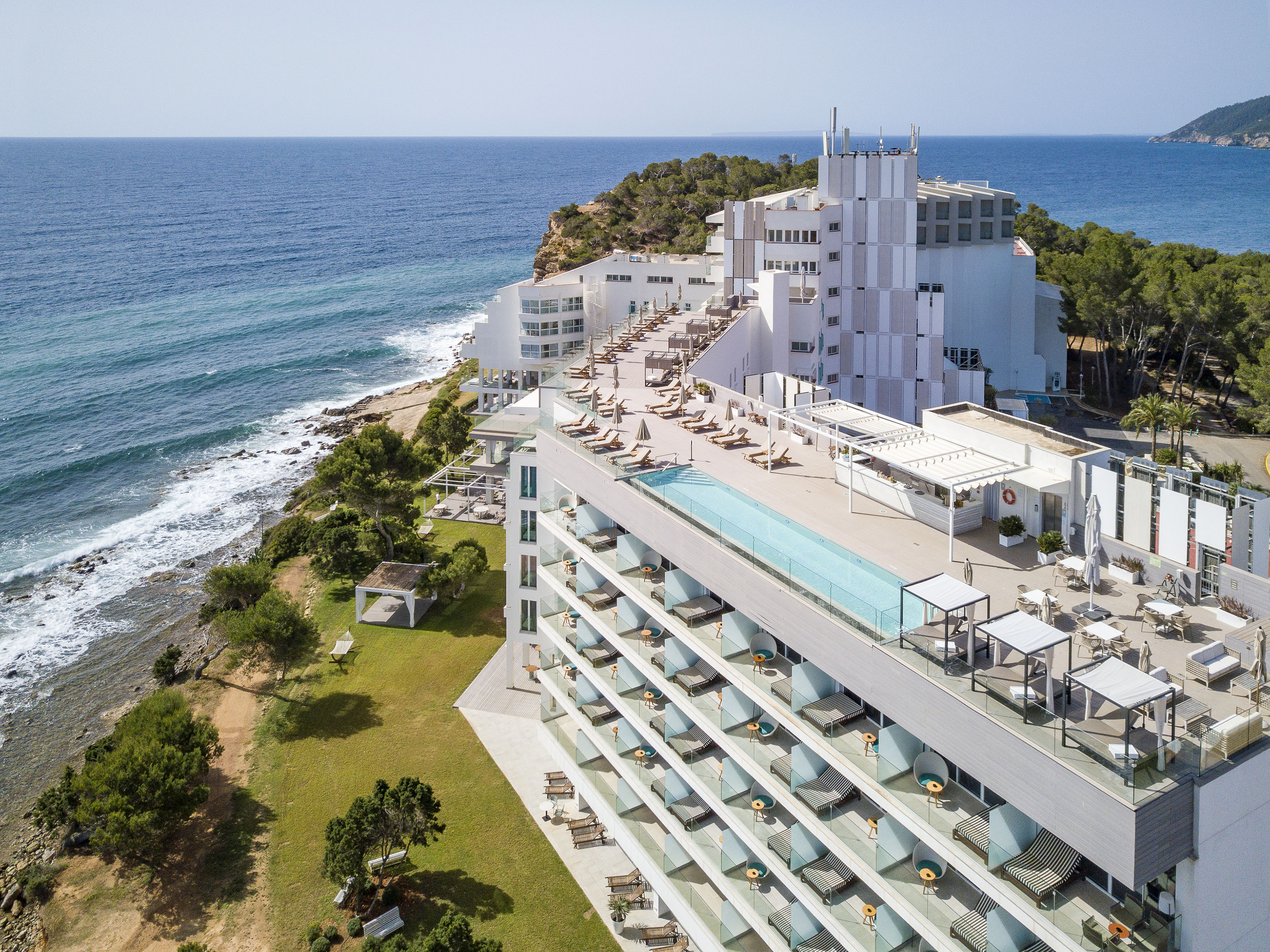 Coastal luxury hotel with rooftop pool and ocean view balconies.