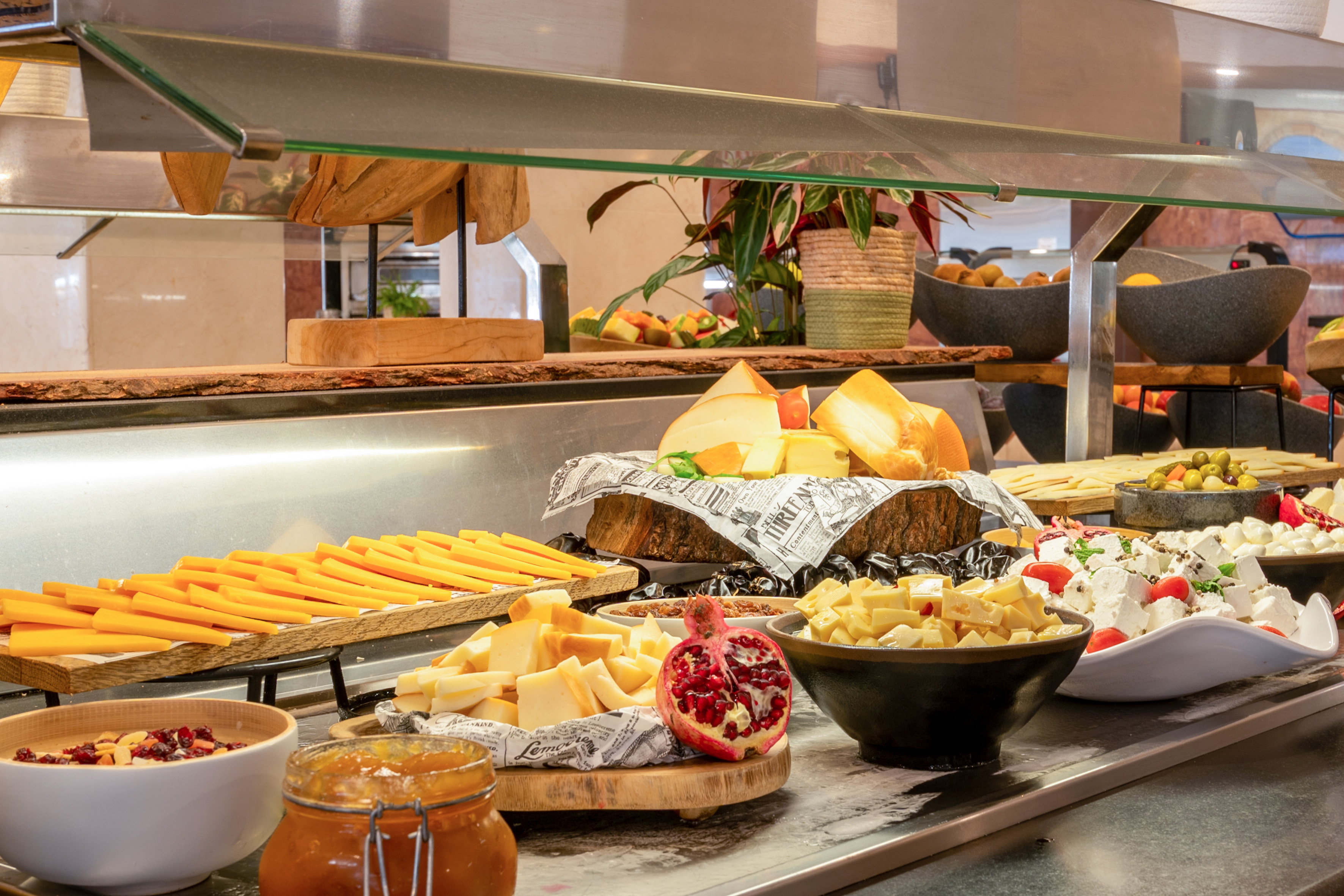 Assorted cheese buffet with olives, pomegranate, jam, and feta.