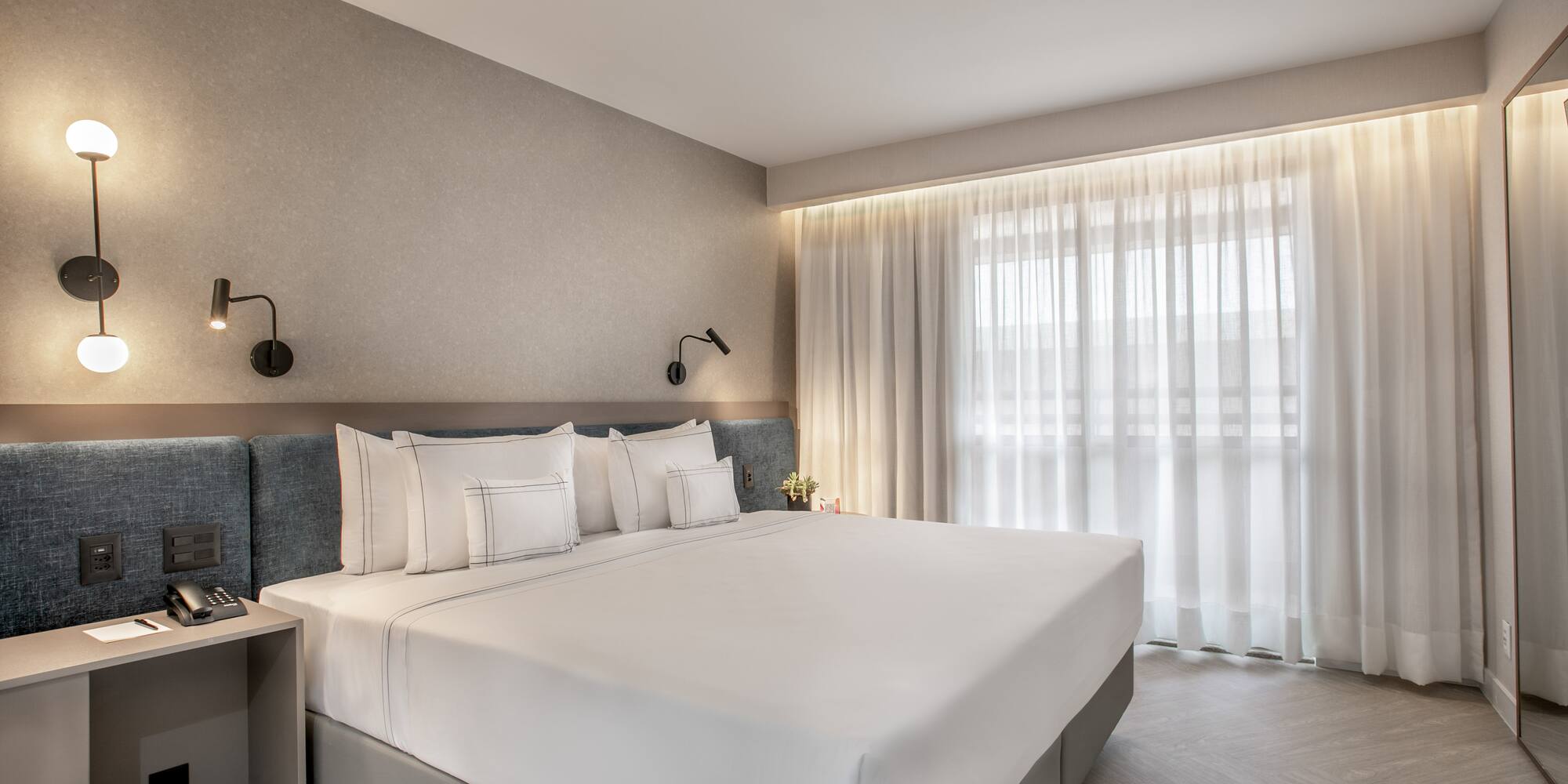 a bed with white sheets and pillows in a room