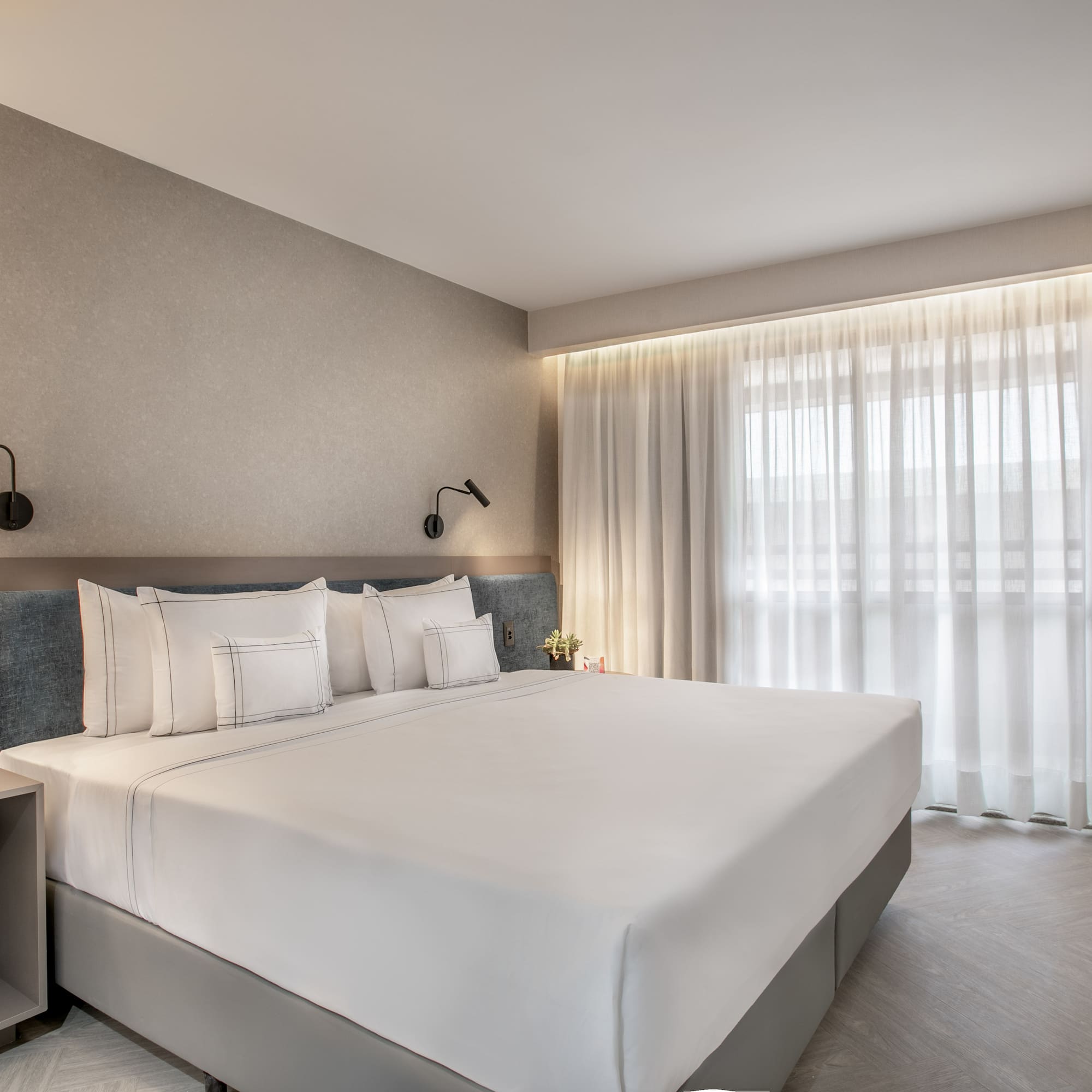 a bed with white sheets and pillows in a room