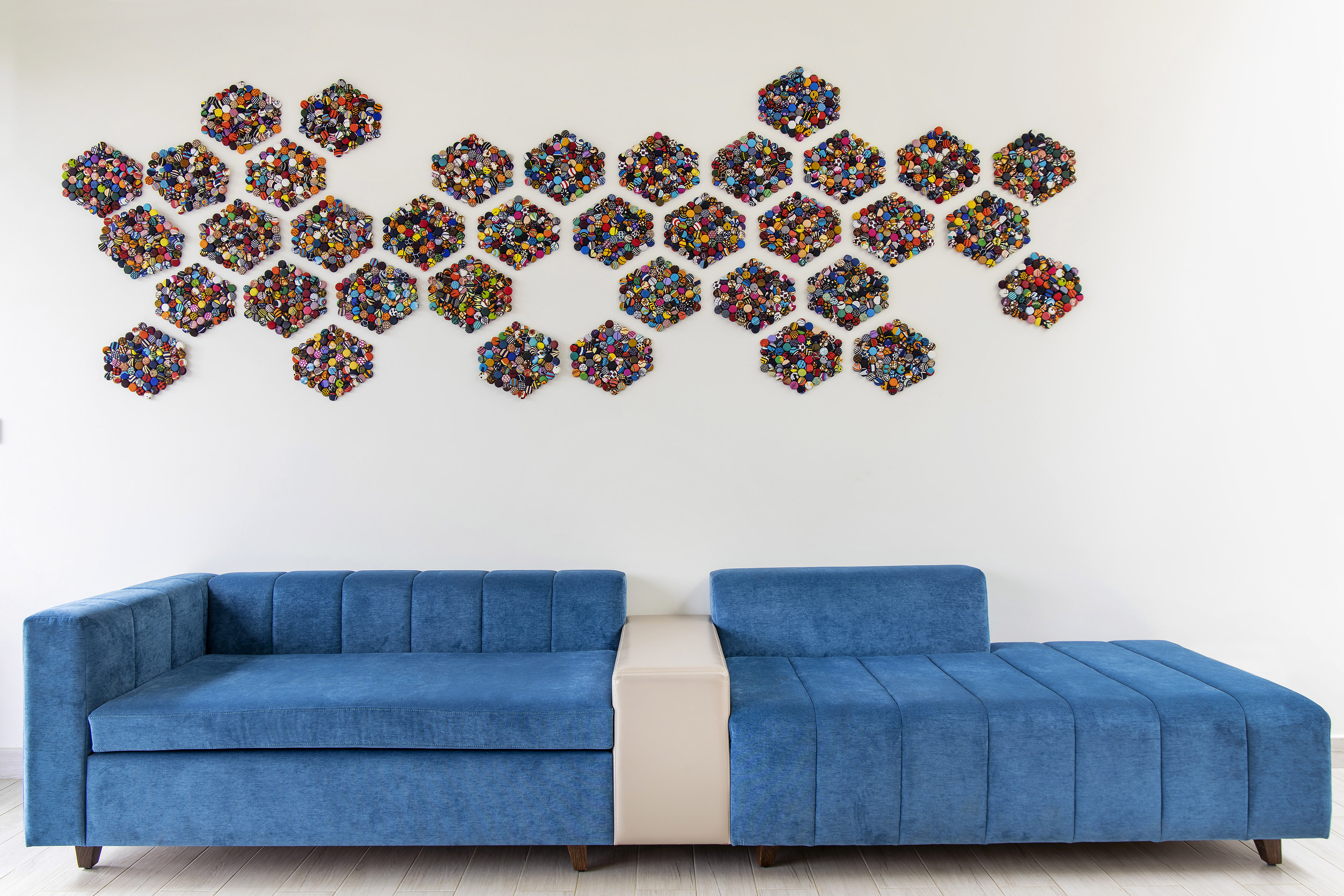 Living room with blue sectional sofa, vibrant honeycomb button art.