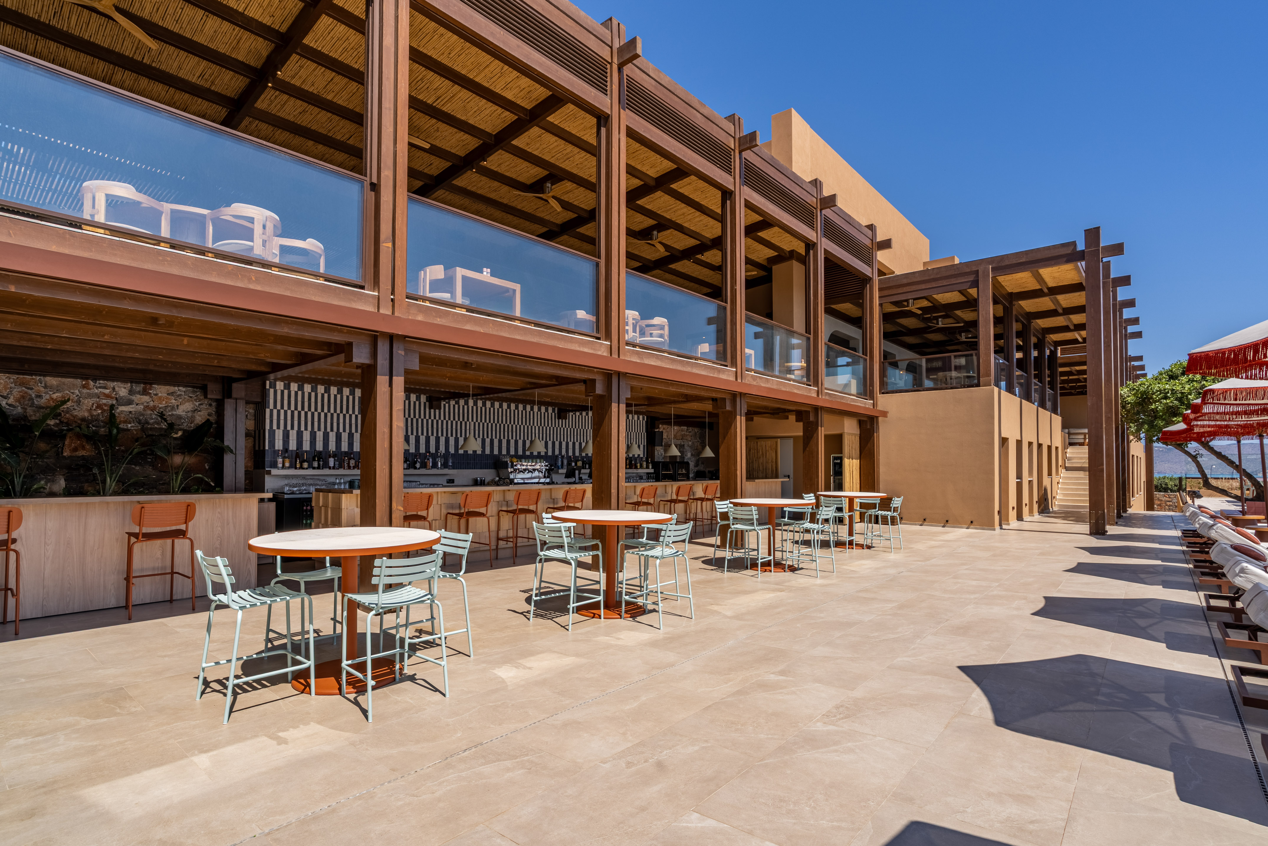 Modern resort outdoor patio and bar area with dining tables, wooden structure.