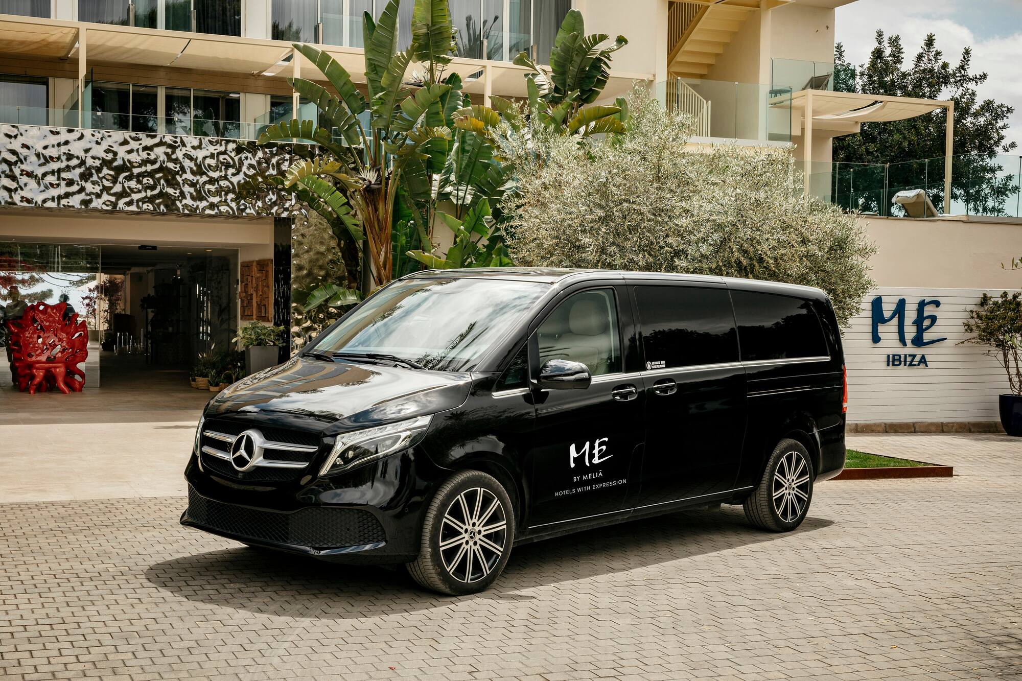 Black Mercedes-Benz van parked at ME Ibiza hotel entrance.