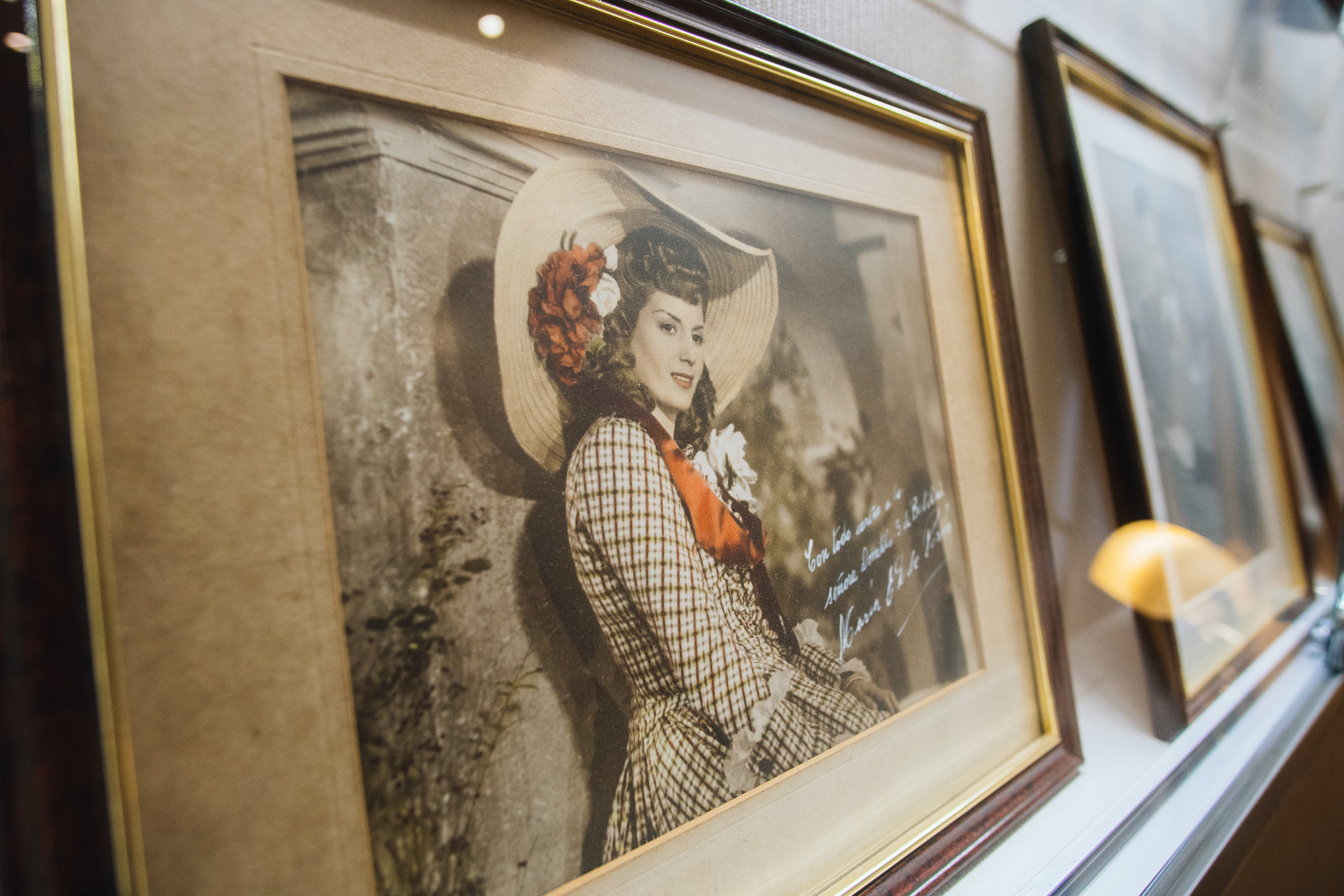 Framed retro portrait of woman in wide hat, red flowers, plaid dress, signed.