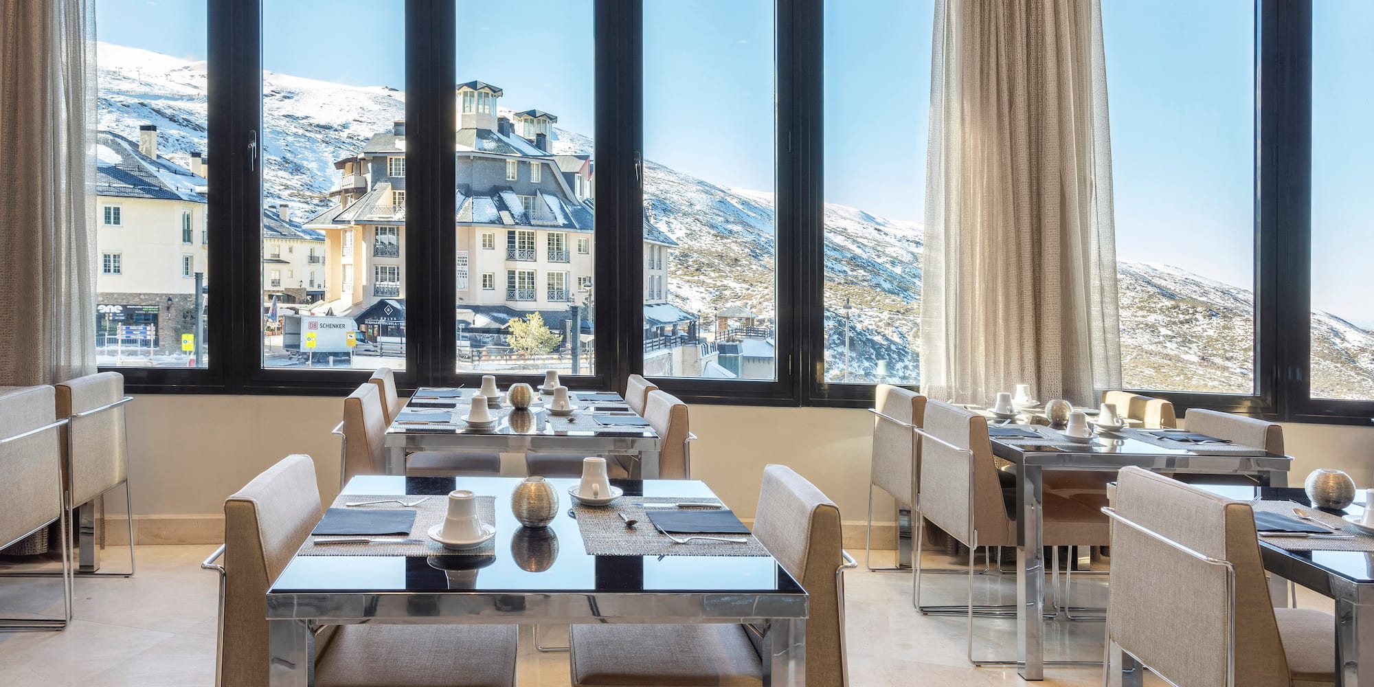 a room with tables and chairs and a view of a snowy mountain