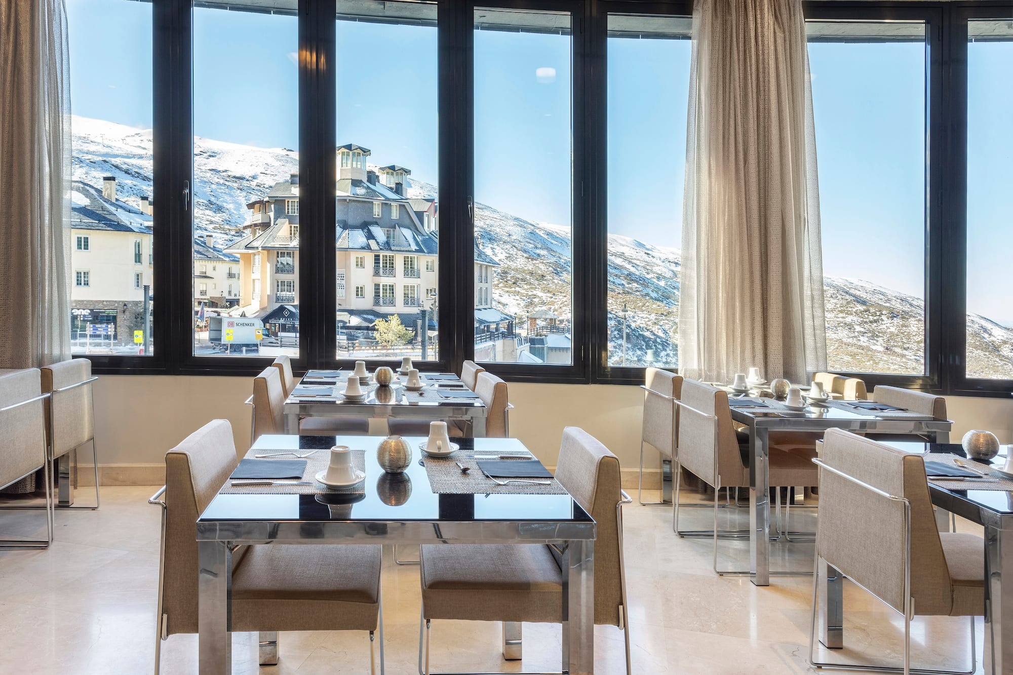 a room with tables and chairs and a view of a snowy mountain