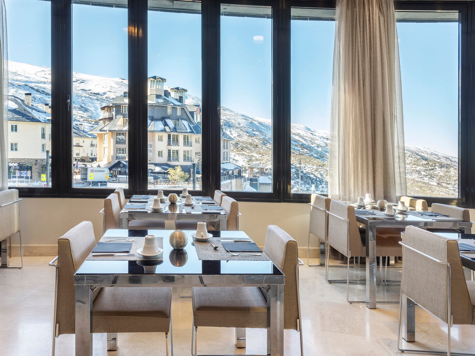 a room with tables and chairs and a view of a snowy mountain