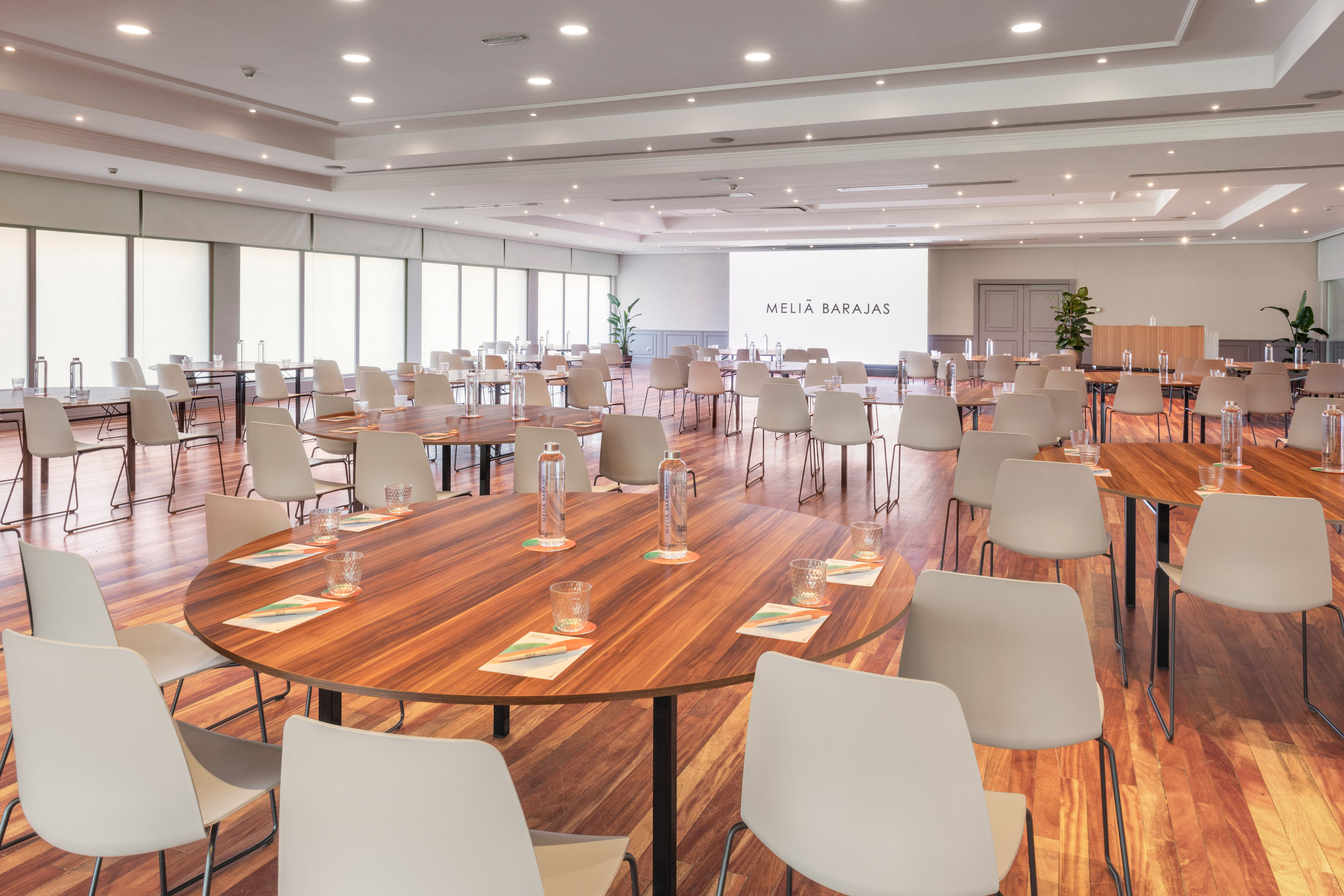 Spacious Melia Barajas meeting room with modern tables, chairs, and screen.