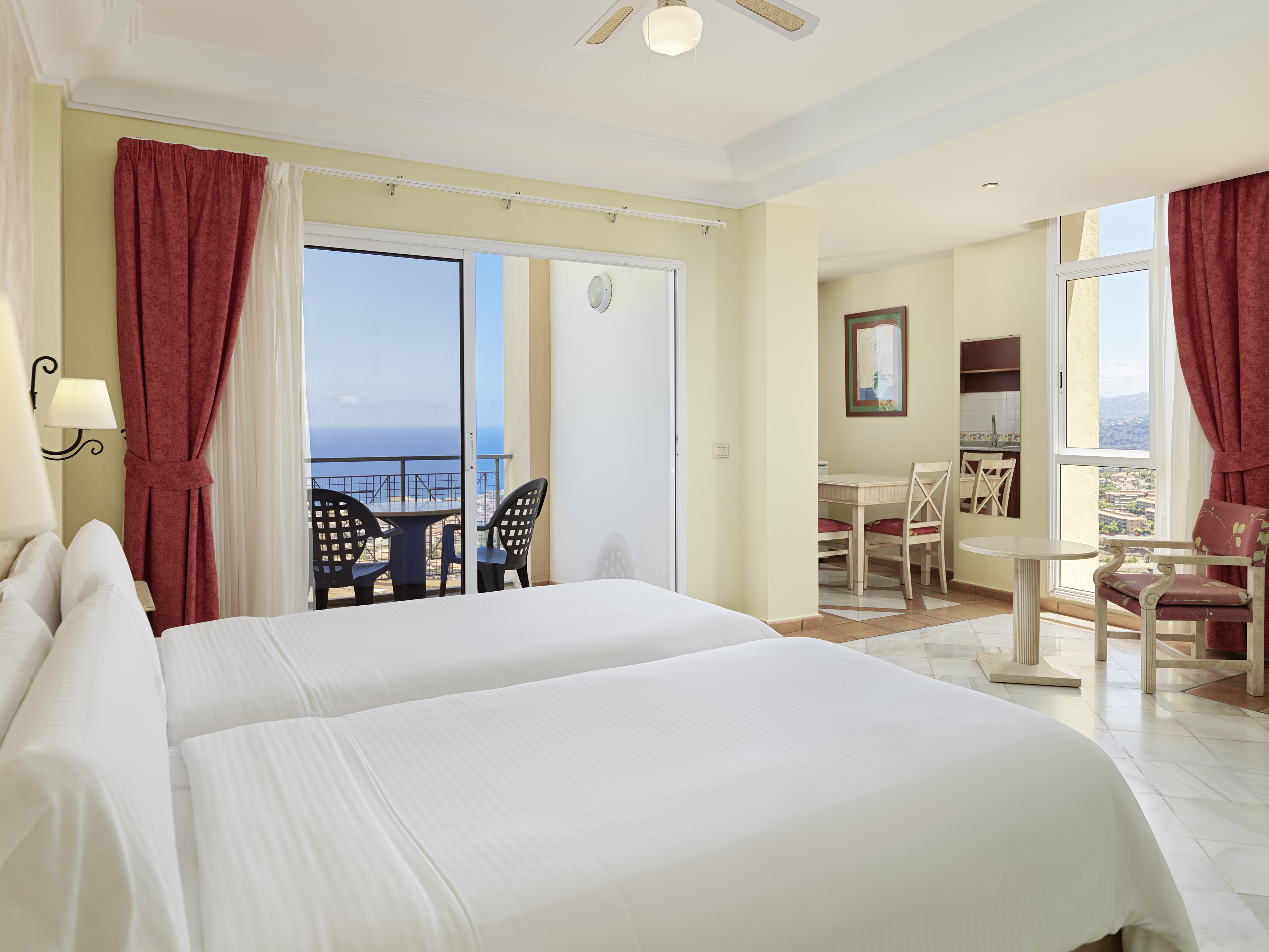 a room with two beds and a balcony overlooking the ocean