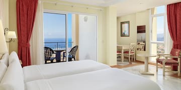 a room with two beds and a balcony overlooking the ocean