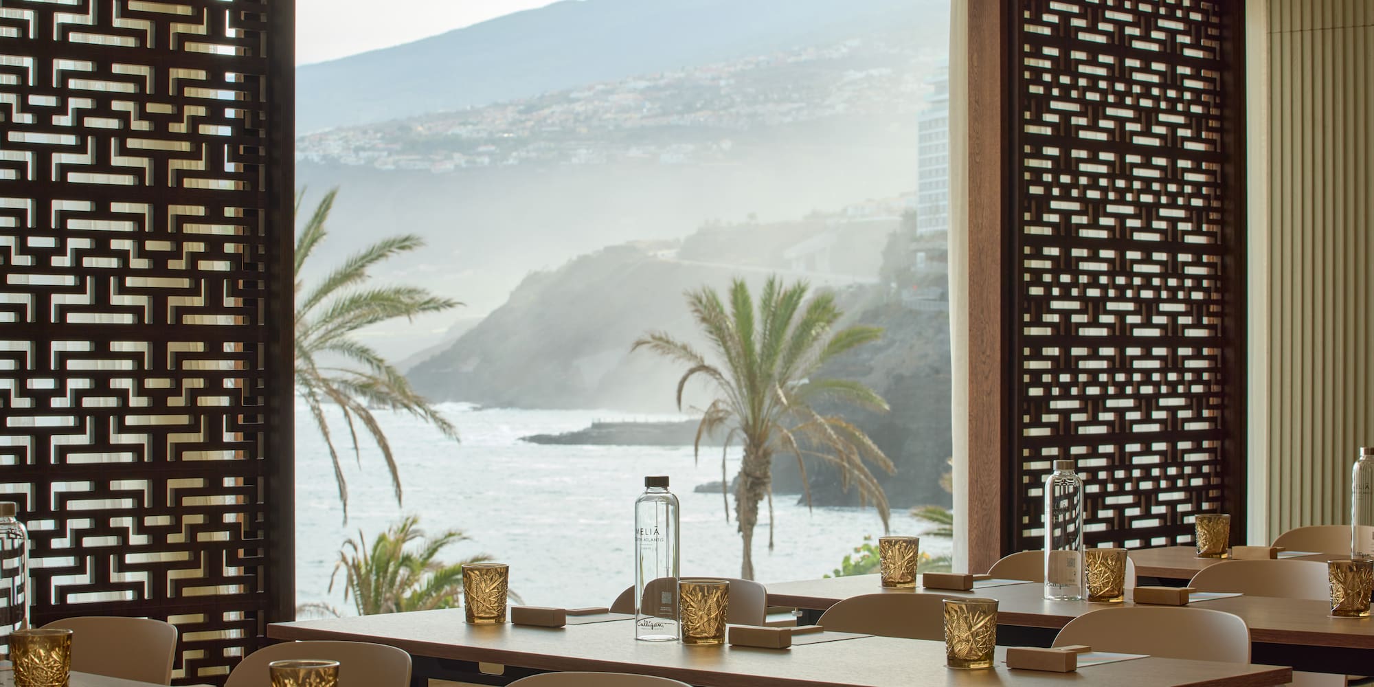 a room with tables and chairs and a view of the ocean