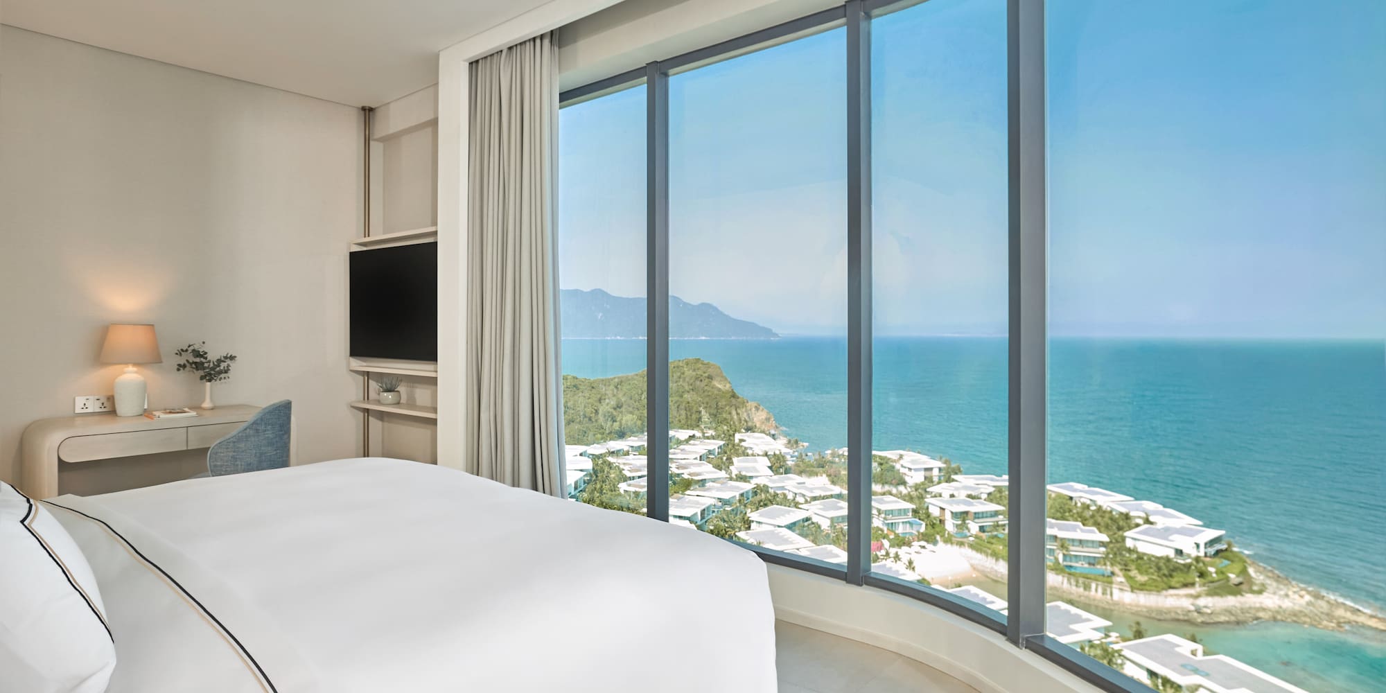 Modern hotel room with panoramic ocean and coastal resort view.