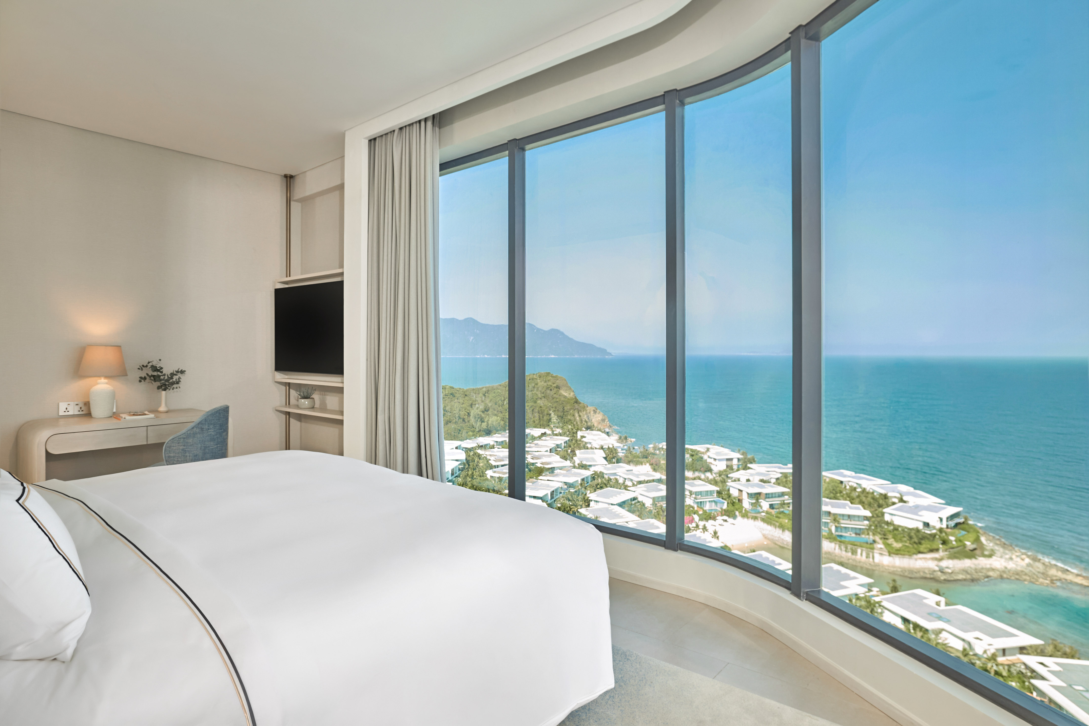 Modern hotel room with panoramic ocean and coastal resort view.