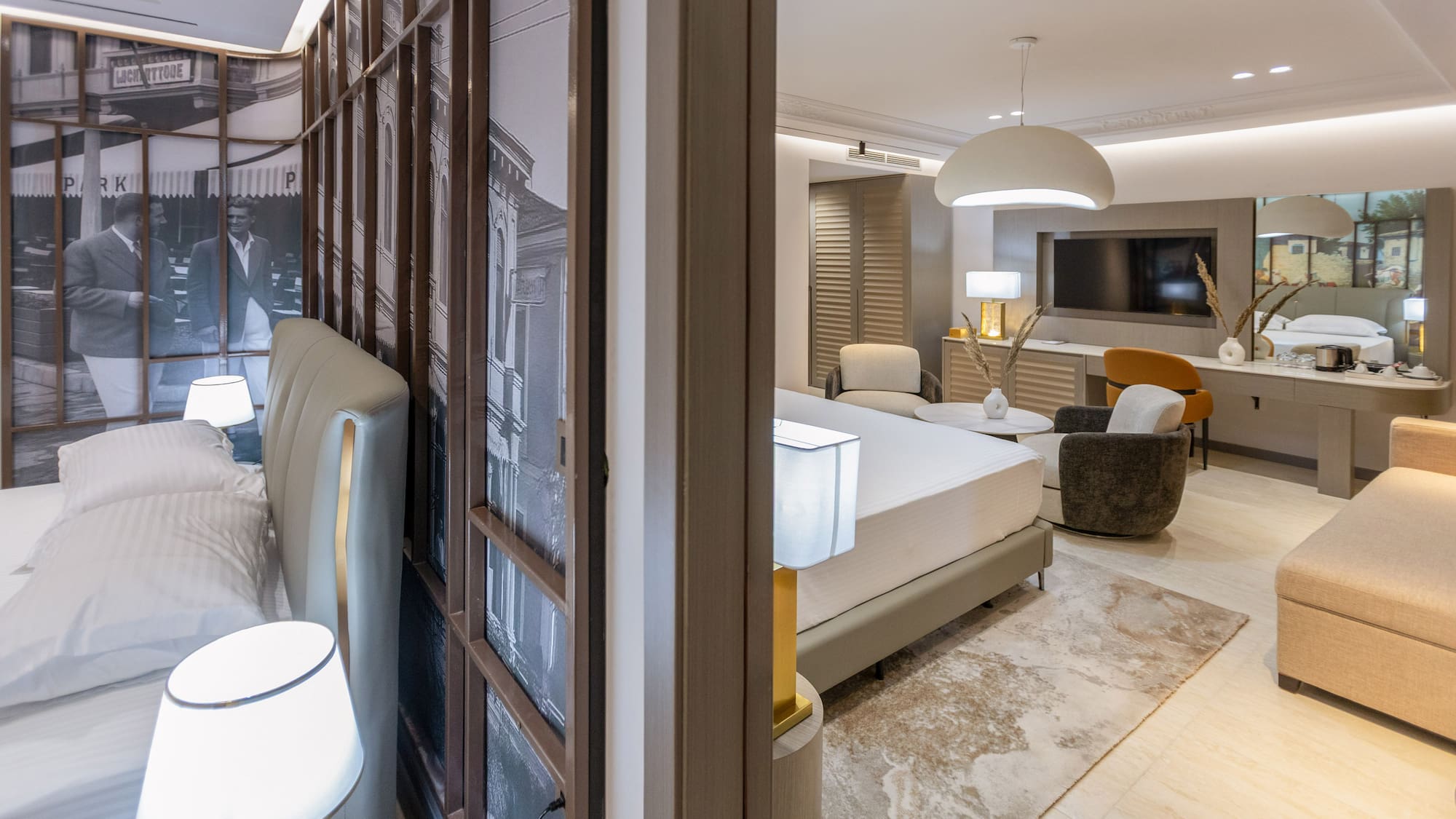 Modern hotel suite with bedroom, spacious living area, and urban wall art.