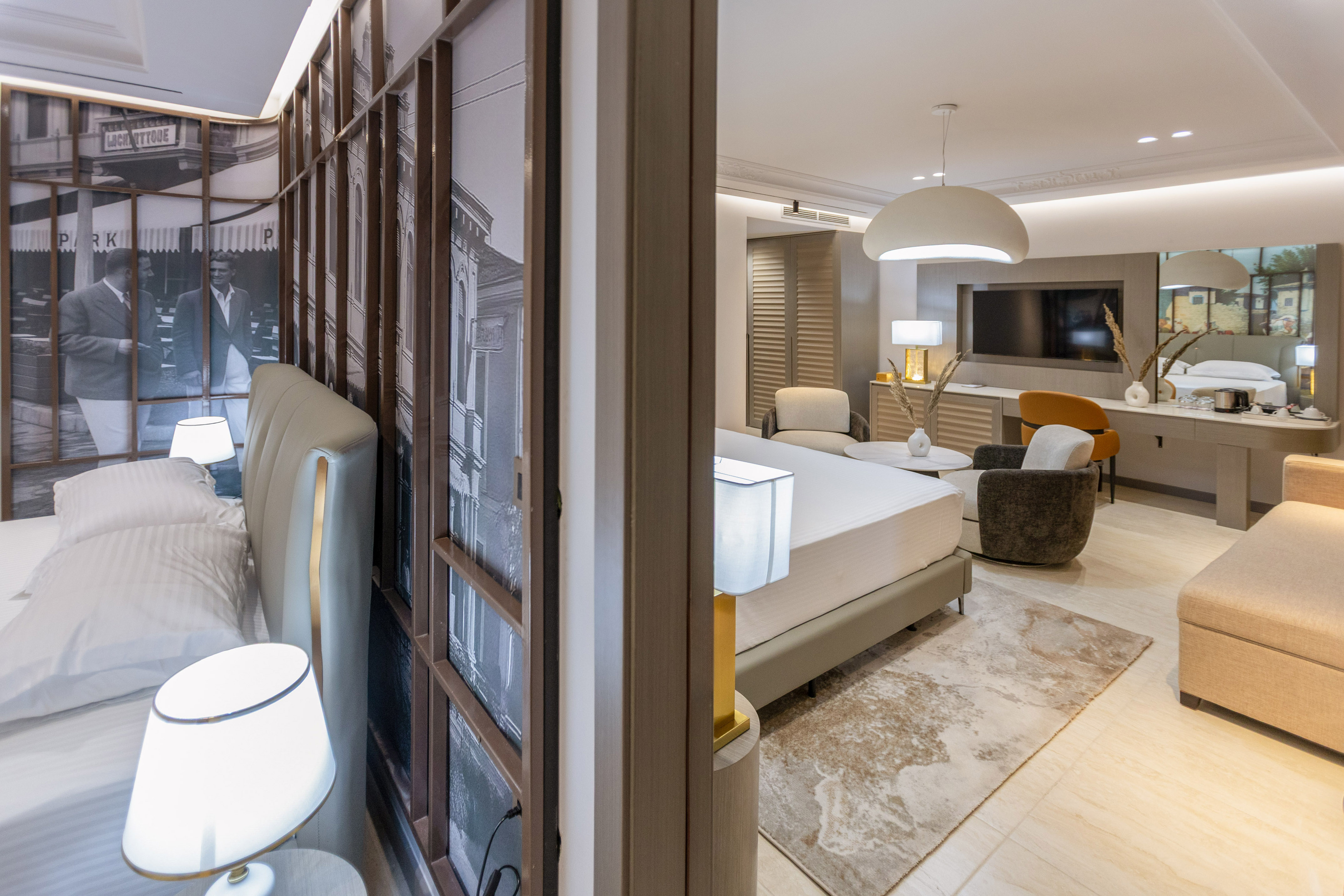 Modern hotel suite with bedroom, spacious living area, and urban wall art.