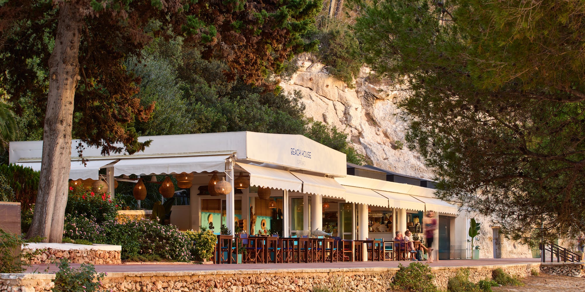 a building with a white awning and a stone wall with trees