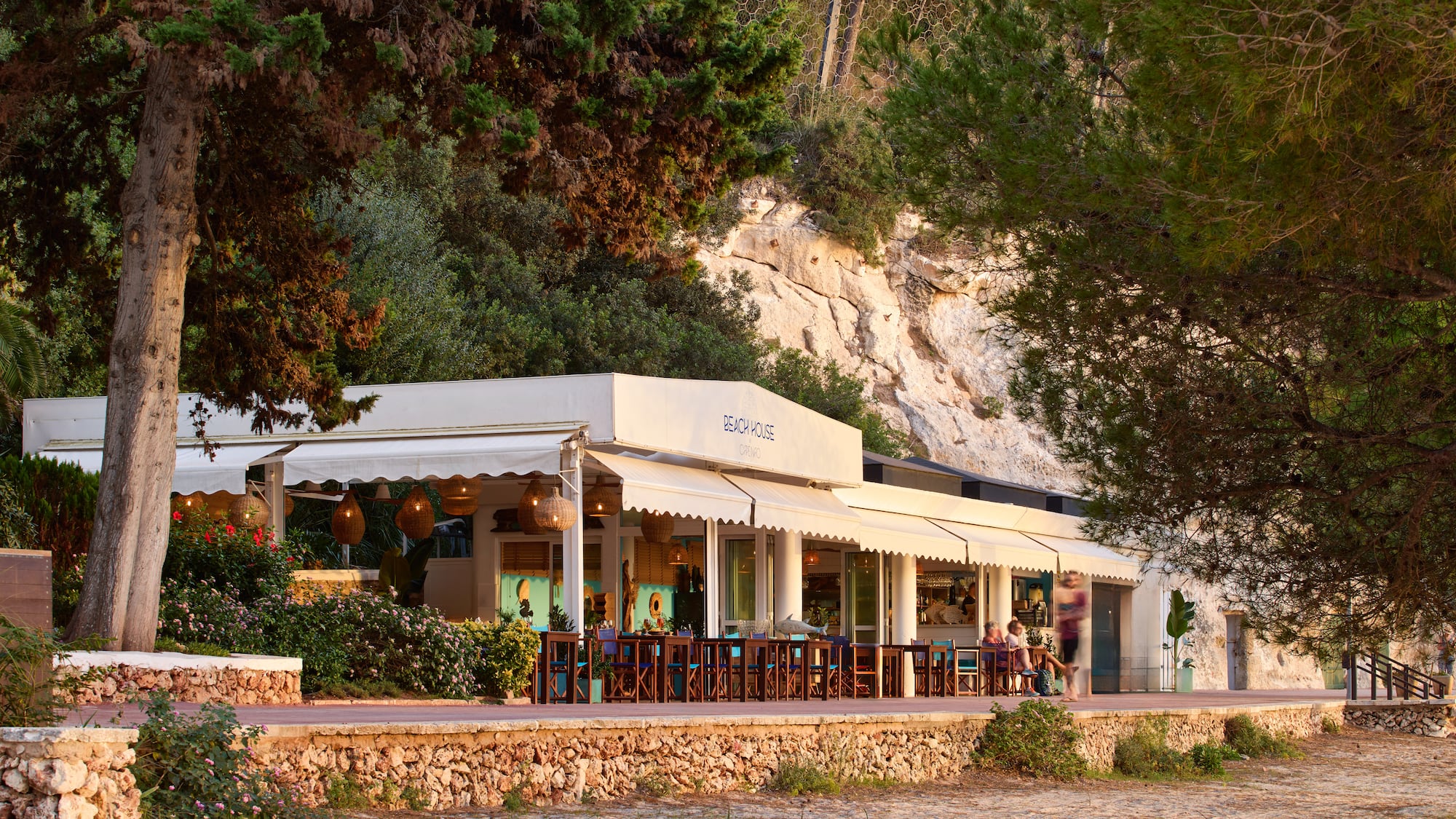 a building with a white awning and a stone wall with trees