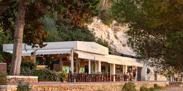 a building with a white awning and a stone wall with trees