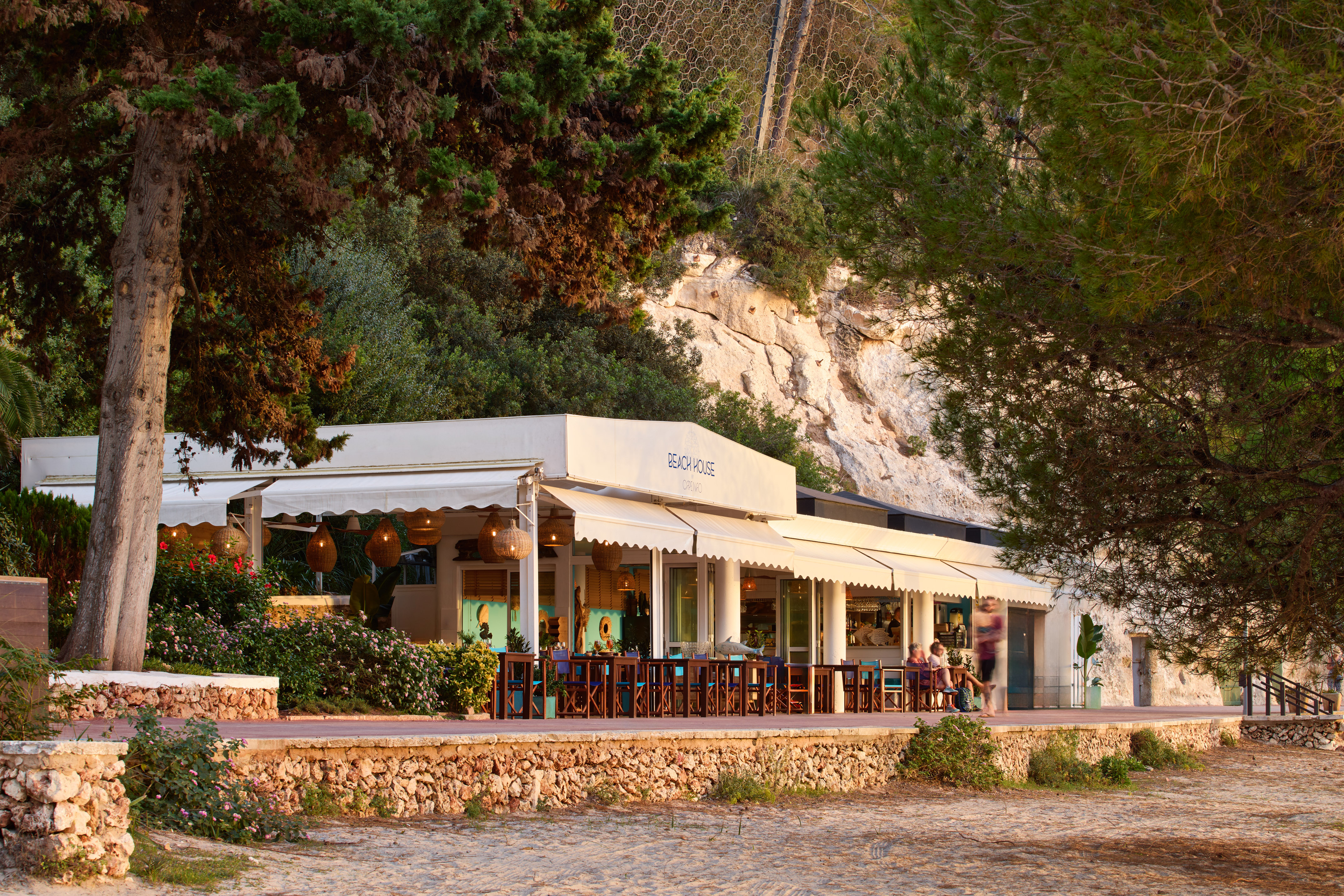 a building with a white awning and a stone wall with trees