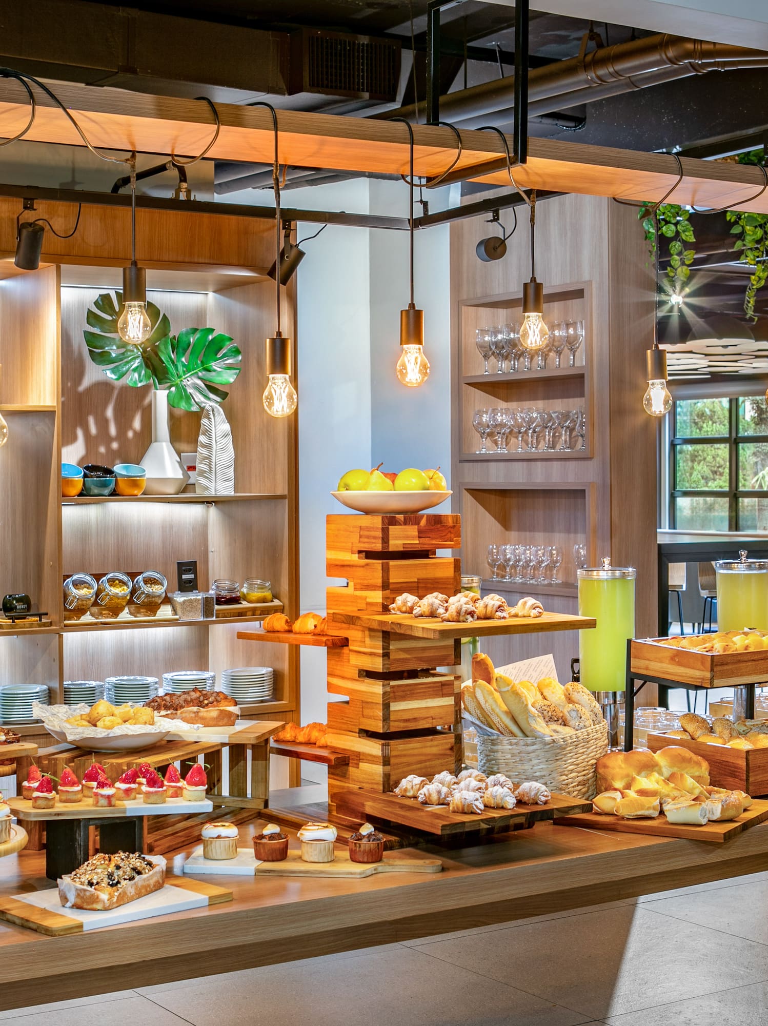 Modern hotel buffet with pastries, bread, fruit, and refreshing drinks.