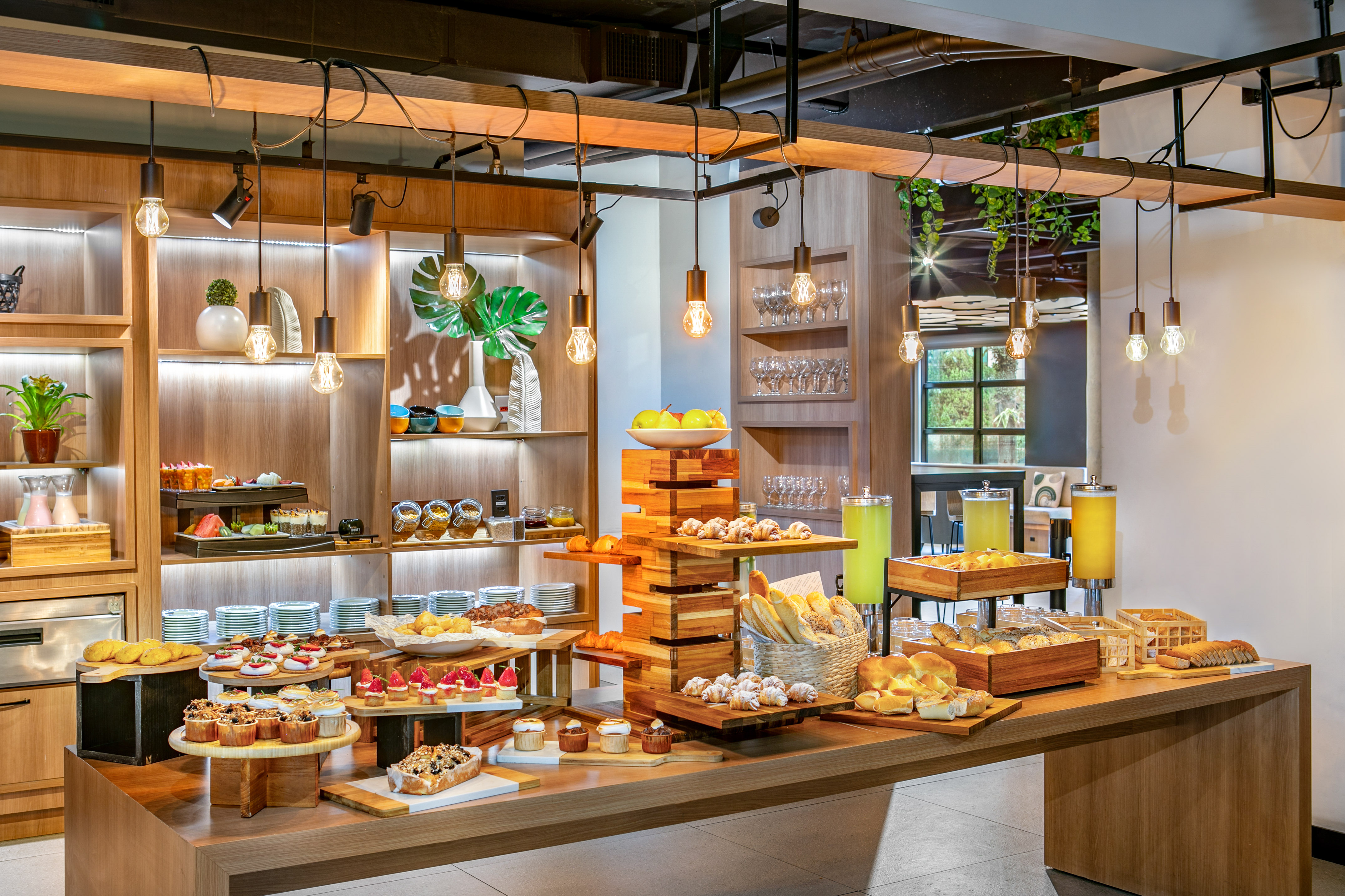 Modern hotel buffet with pastries, bread, fruit, and refreshing drinks.